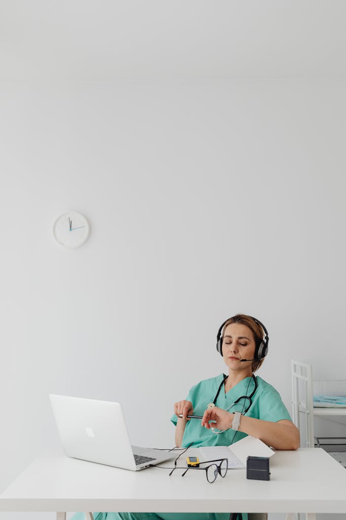 Woman doctor using laptop and headphones for remote medical consultation.